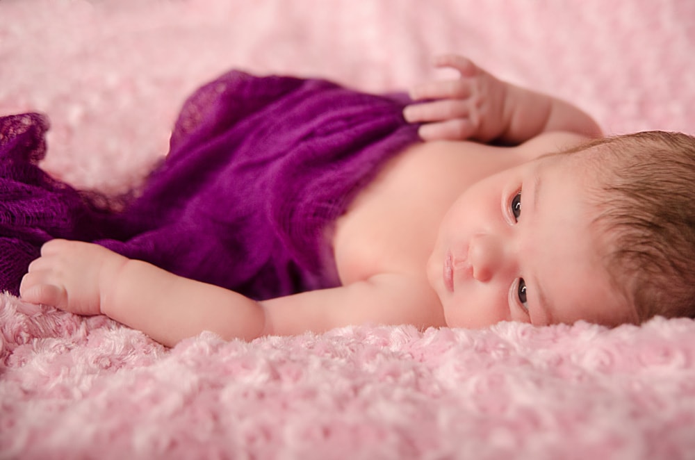 baby with purple blanket