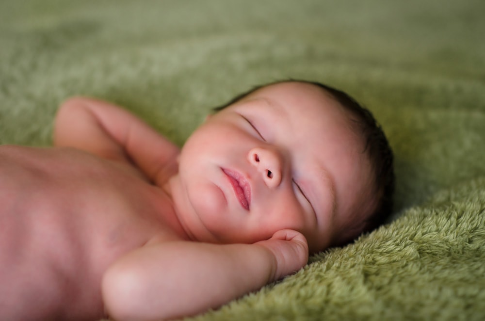 newborn baby boy sleeping on green blanket