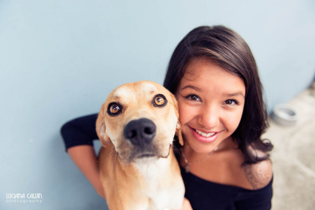 Teen in front of blue wall with dog posing for photo shoot
