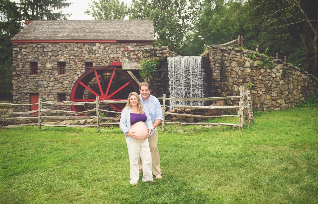 Pregnant couple posing in front of mill