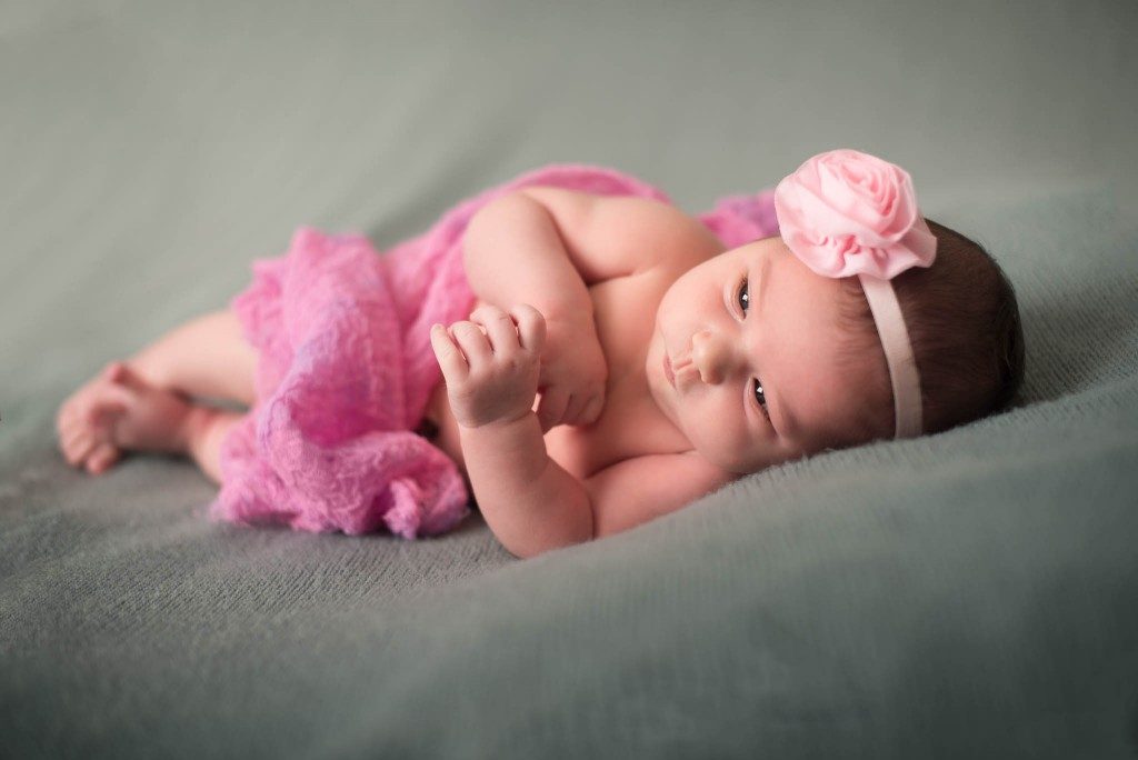 baby in pink laying down on bed