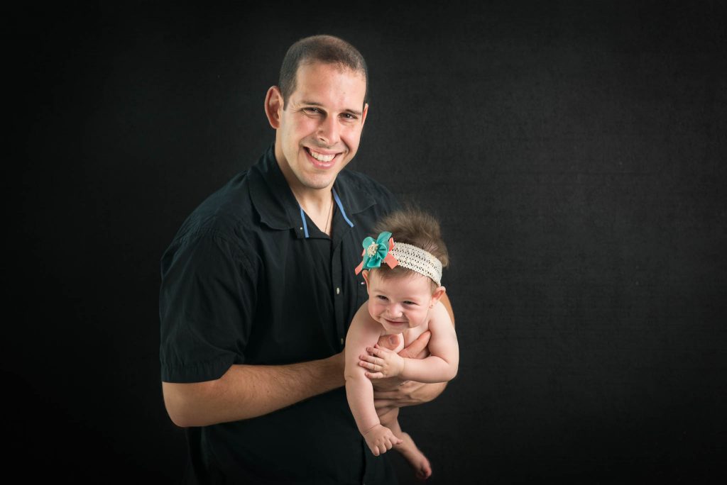 baby girl with father on black background