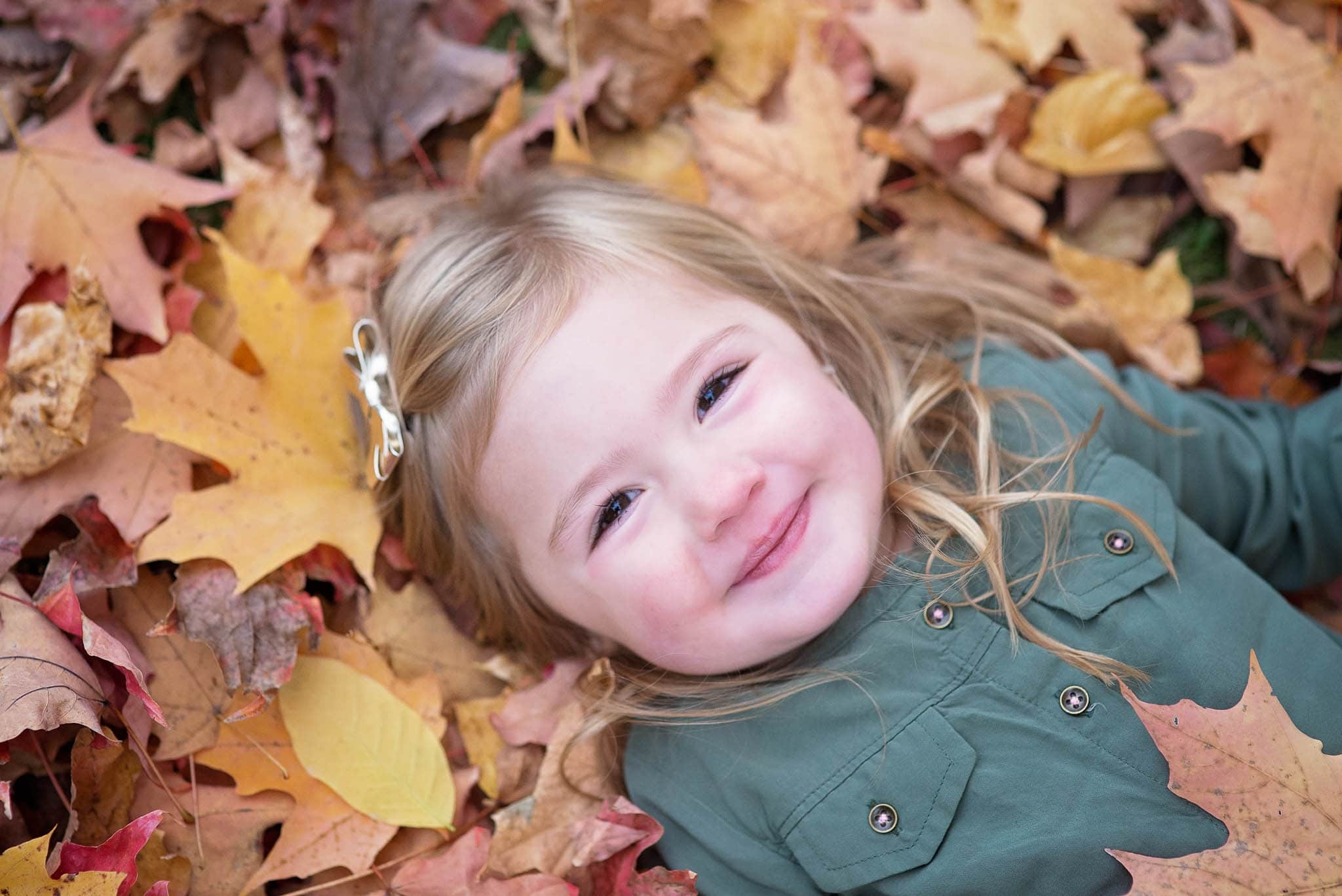 girl laying down on fall leaves