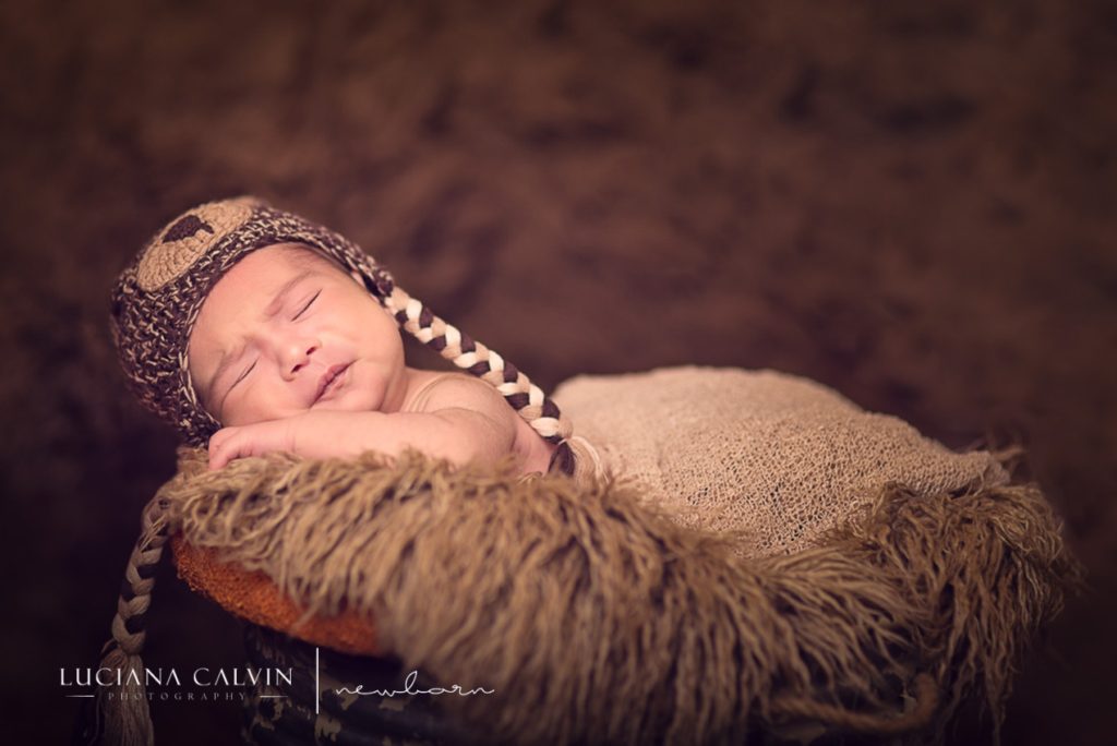 newborn baby making faces while sleeping on a basket