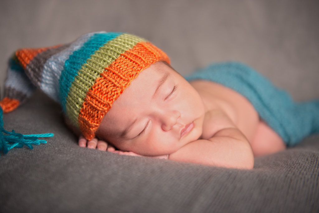 newborn baby sleeping with a colorful hat