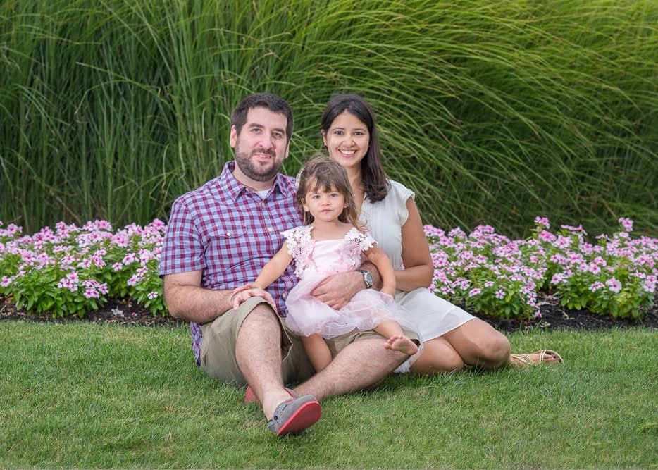 Family seating on green grass in East Boston for photo session