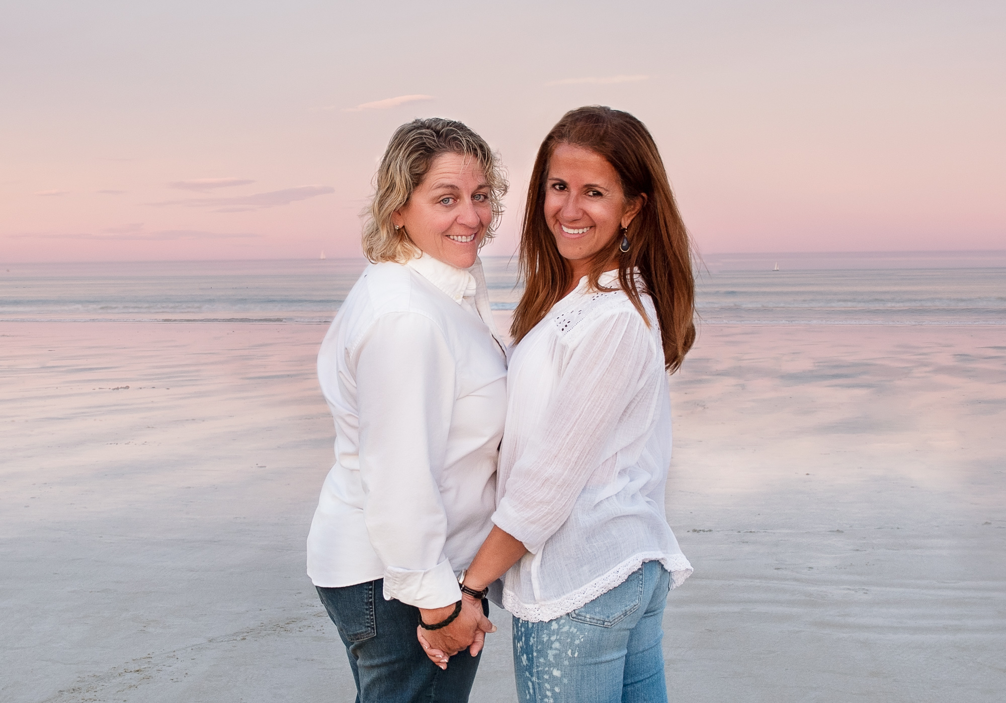 Couple holding hands at beach at sunset which is the best time for photos outside