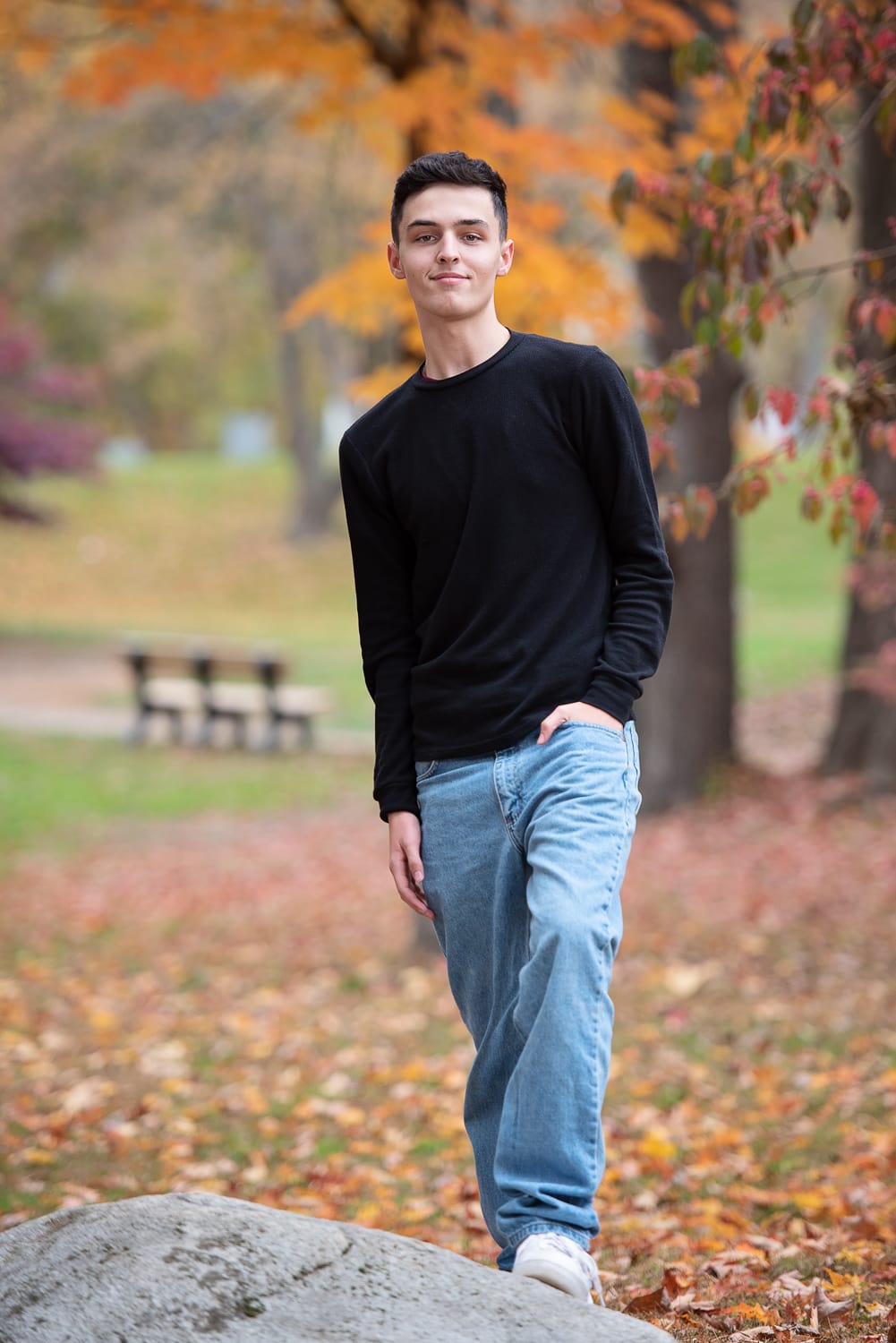 senior portrait in the fall by a pond sitting on a rock at great brook farm park in carlisle, ma