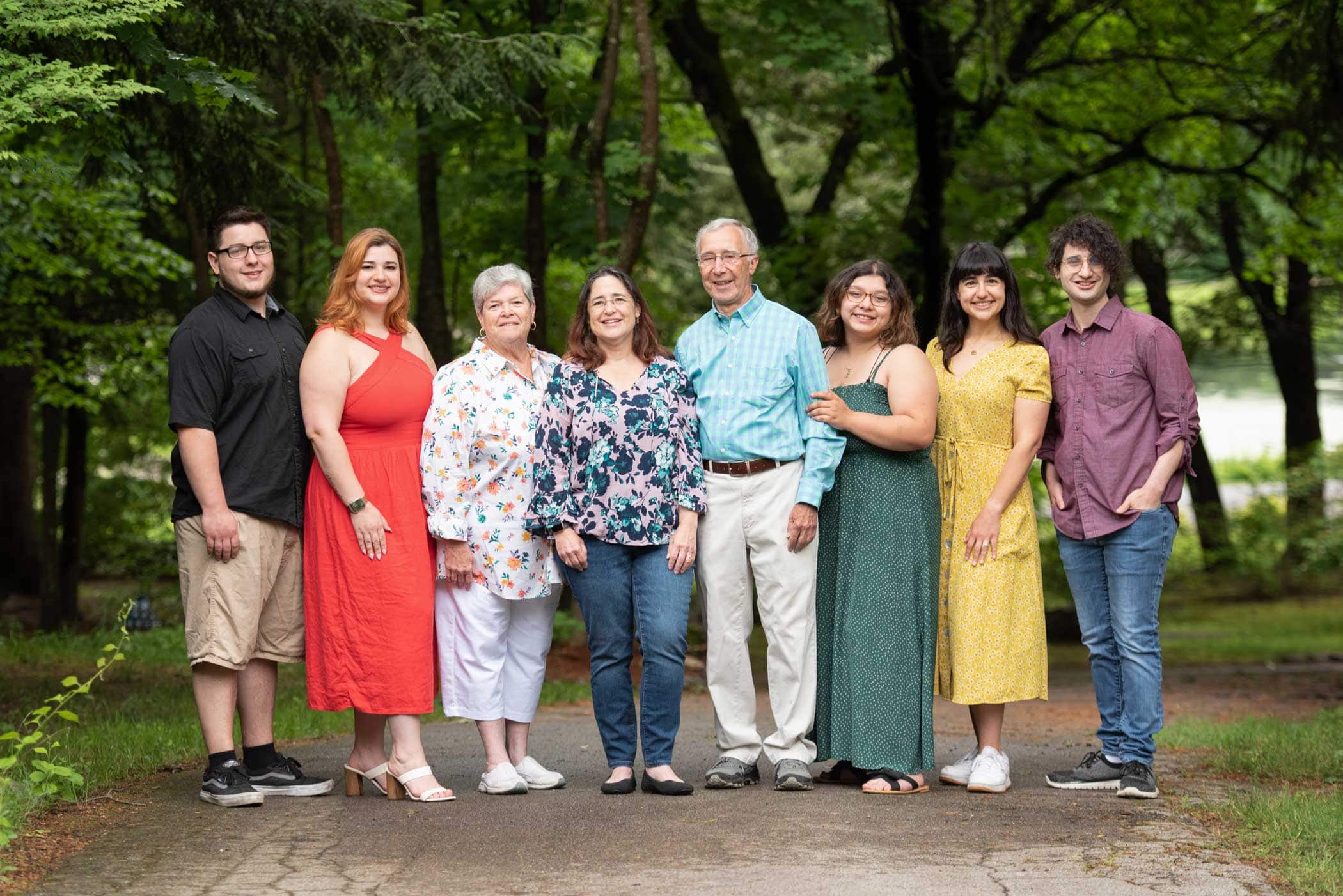 Extended family of nine standing on the paved path in summer green at Benson Park in Hudson NH