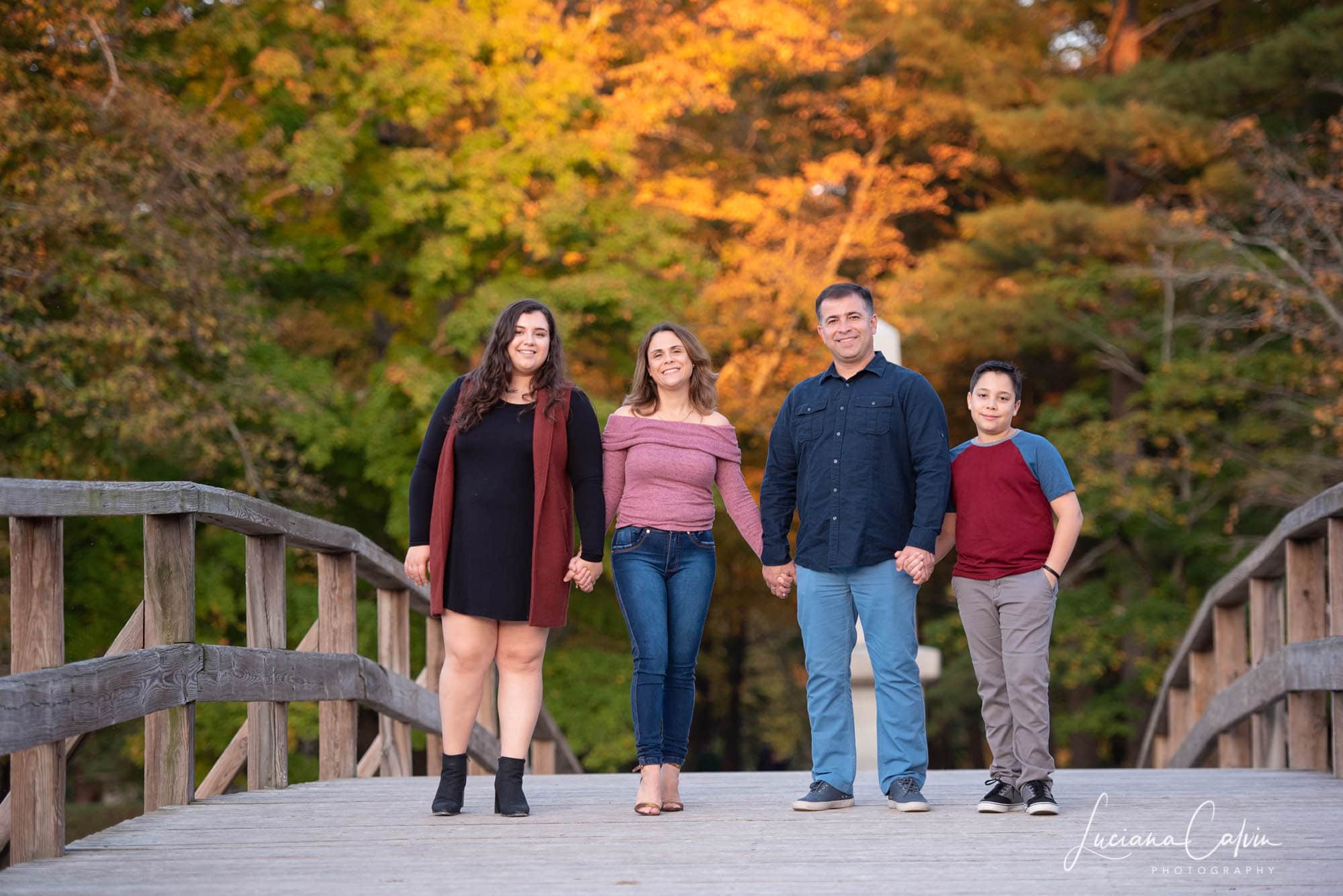 Family of four walking across the Old North Bridge in autumn in Concord MA