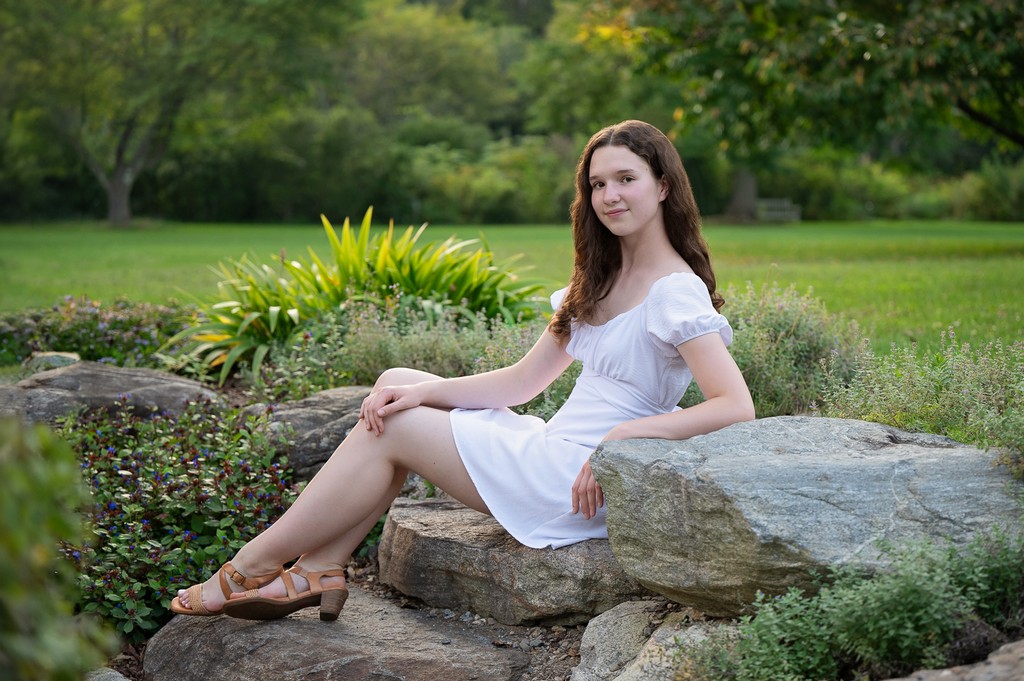 Senior portrait seated on the garden rocks at Acton Arboretum in Acton MA, photographed by Chelmsford portrait photographer Luciana Calvin
