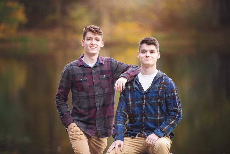 Two senior brothers in flannel shirts by Meadow Pond in autumn at Great Brook Farm in Carlisle MA