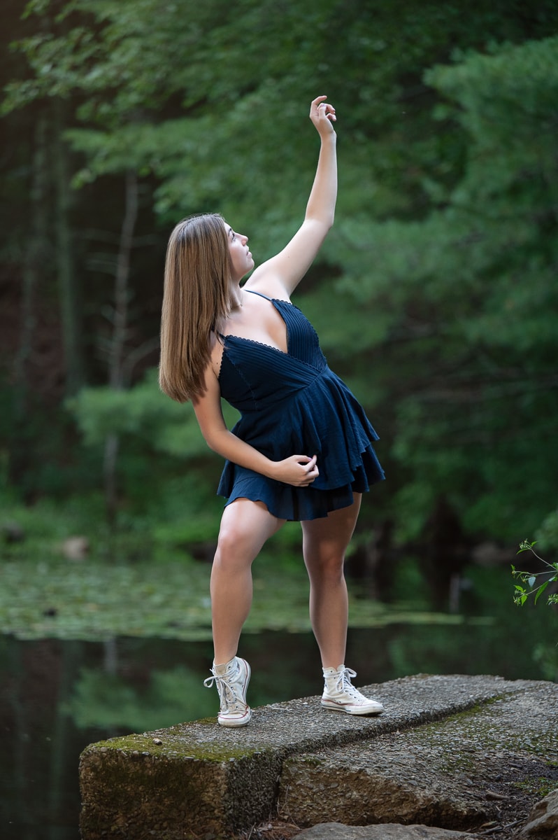 High school senior dancer posed on a rock at the edge of Meadow Pond at Great Brook Farm State Park in Carlisle MA