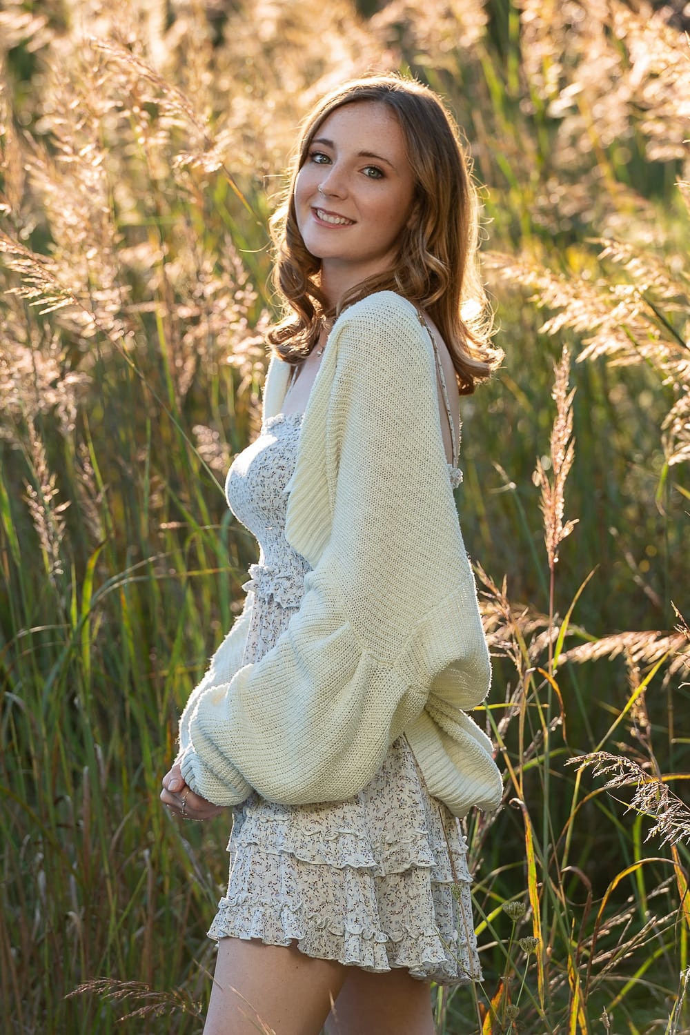 High school senior girl backlit in the tall grass at golden hour at Great Brook Farm, Carlisle Massachusetts