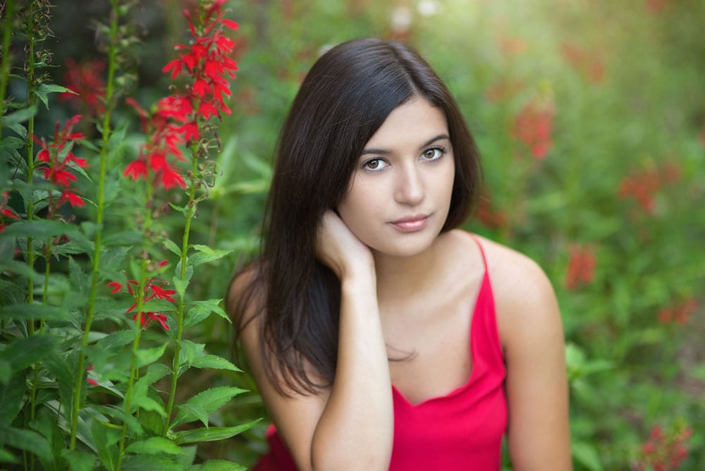 Senior portrait closeup with red flowers in a garden near Chelmsford, MA