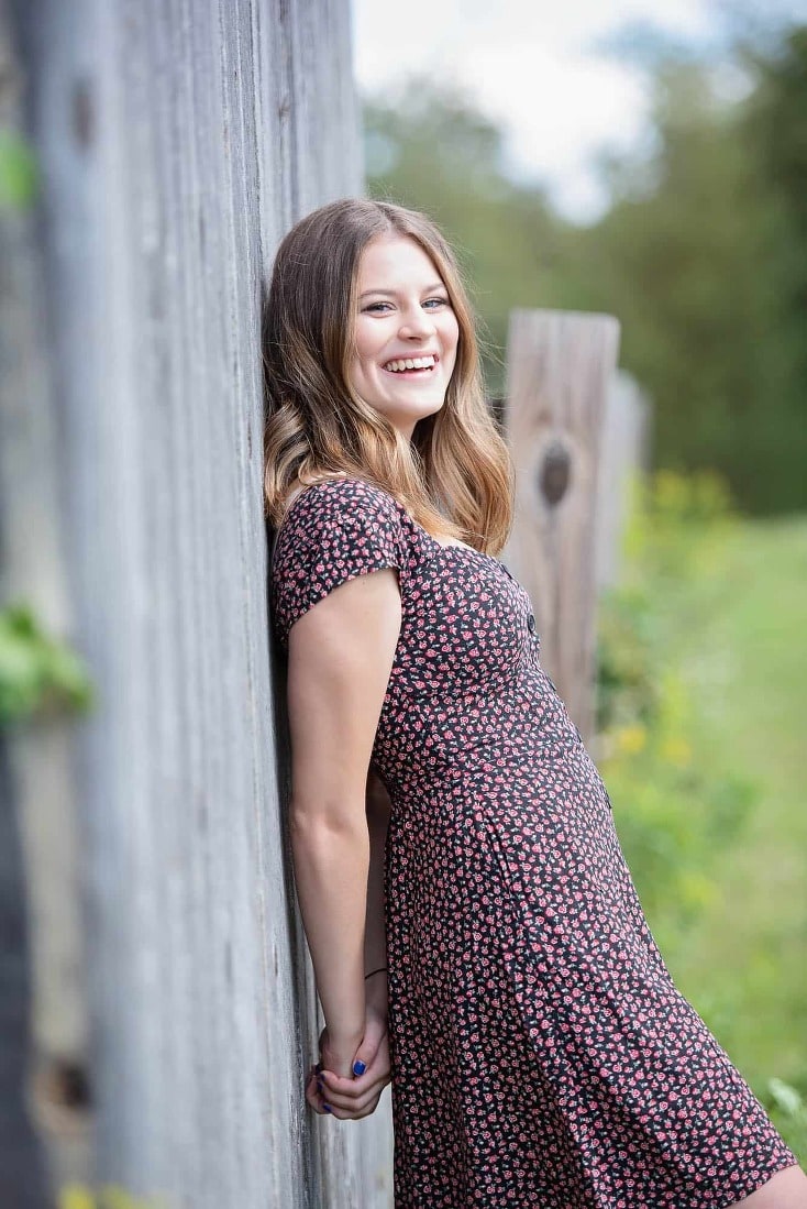 Senior portrait in a farmhouse by a rustic fence near Chelmsford, ma