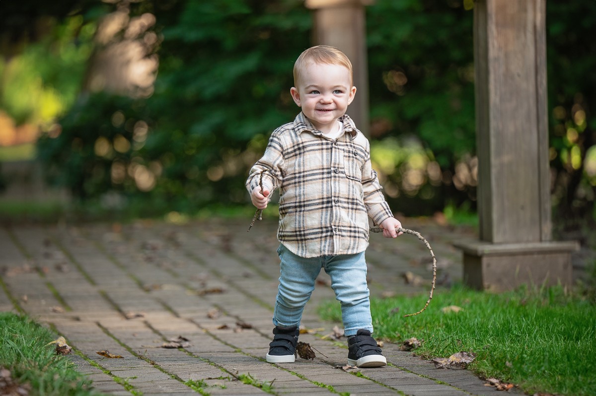 Small boy standing on the brick walkway beside a stone post at Benson Park in Hudson NH