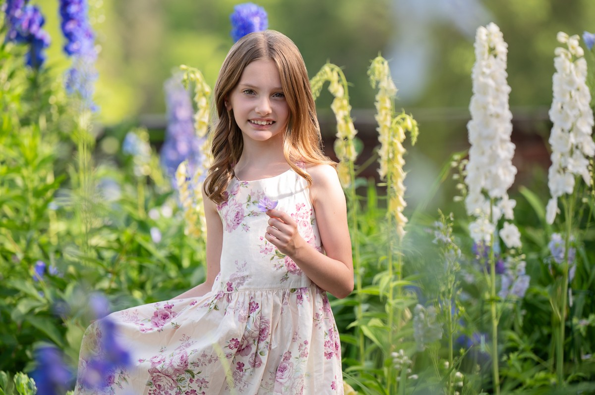 Young girl in a floral dress among the perennial borders of the Buttrick Gardens in Concord MA
