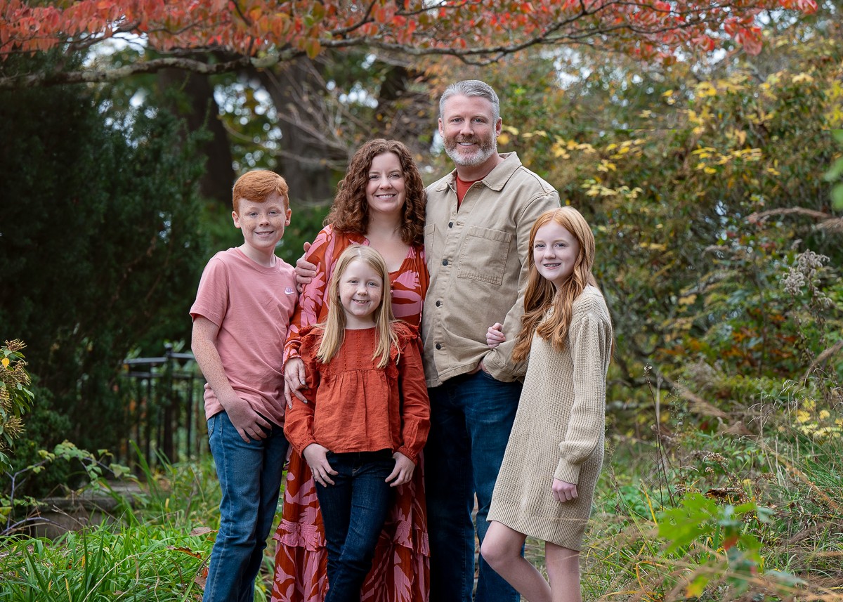 Family of five in front of a red maple at the Old North Bridge in Concord MA