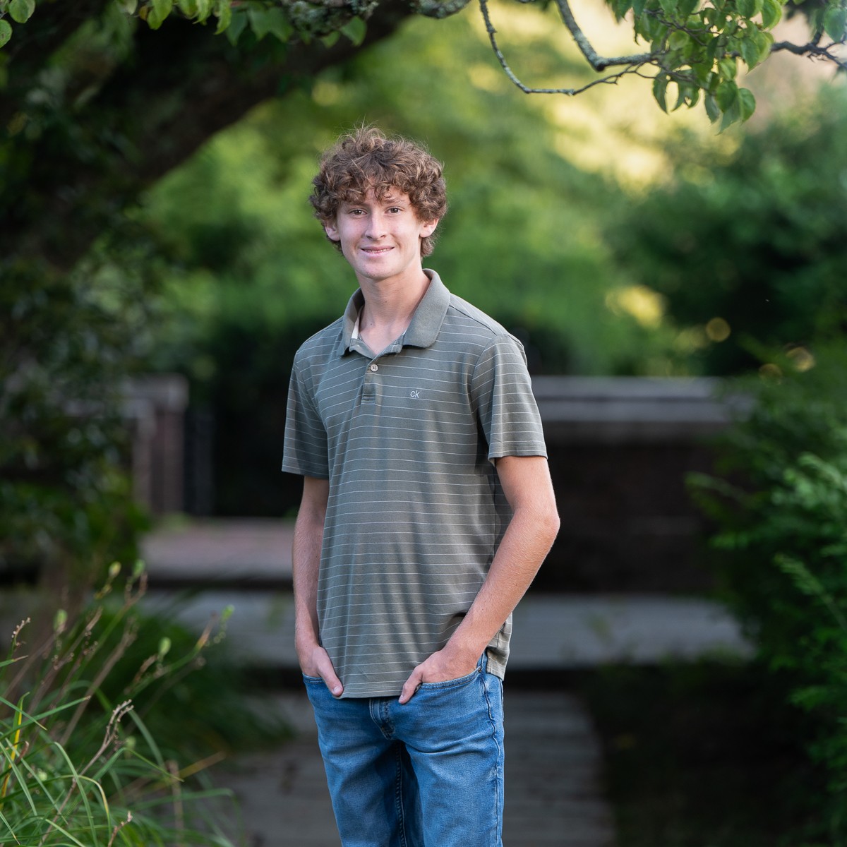 High school senior boy standing under a tree in a summer garden in Concord Massachusetts