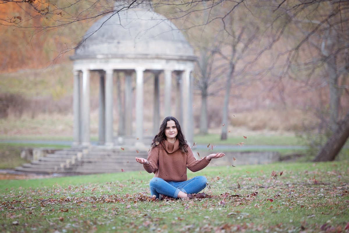 High school senior seated on the lawn below the classical colonnade at Larz Anderson Park in Brookline MA