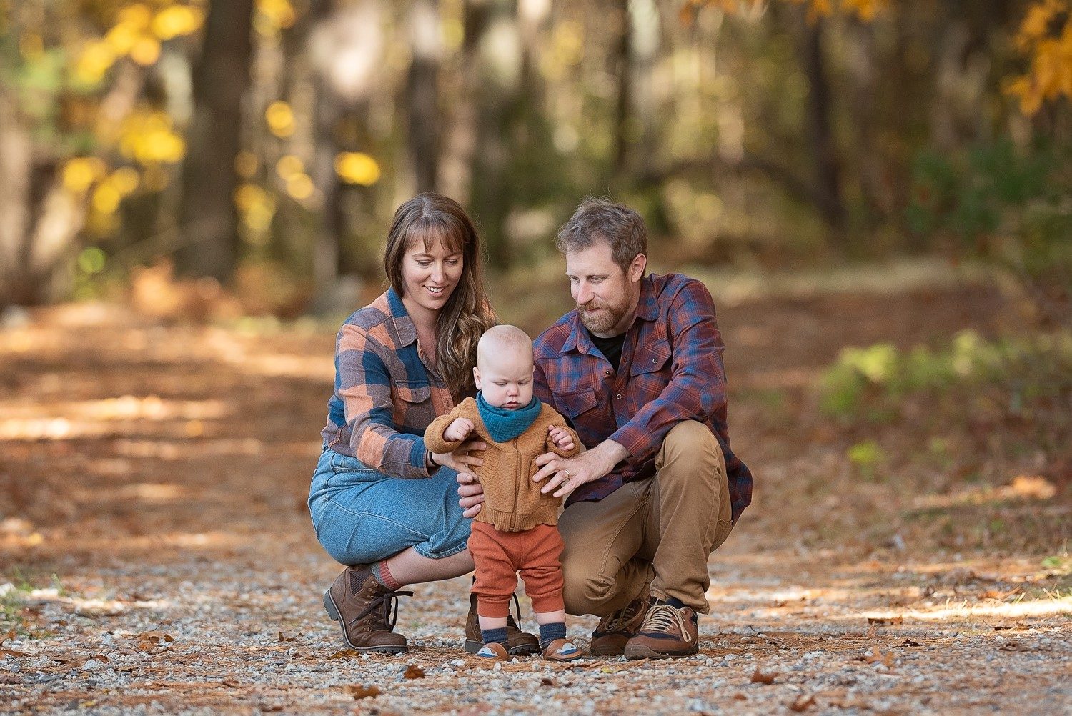 Parents crouched with their toddler on a gravel way under a gold canopy at Assabet River National Wildlife Refuge in Sudbury MA