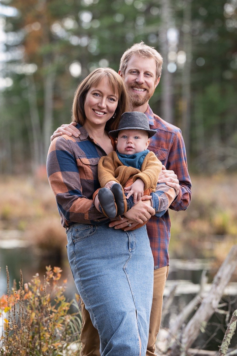 Parents holding their baby while standing in tall autumn grasses at Assabet River National Wildlife Refuge in Sudbury MA