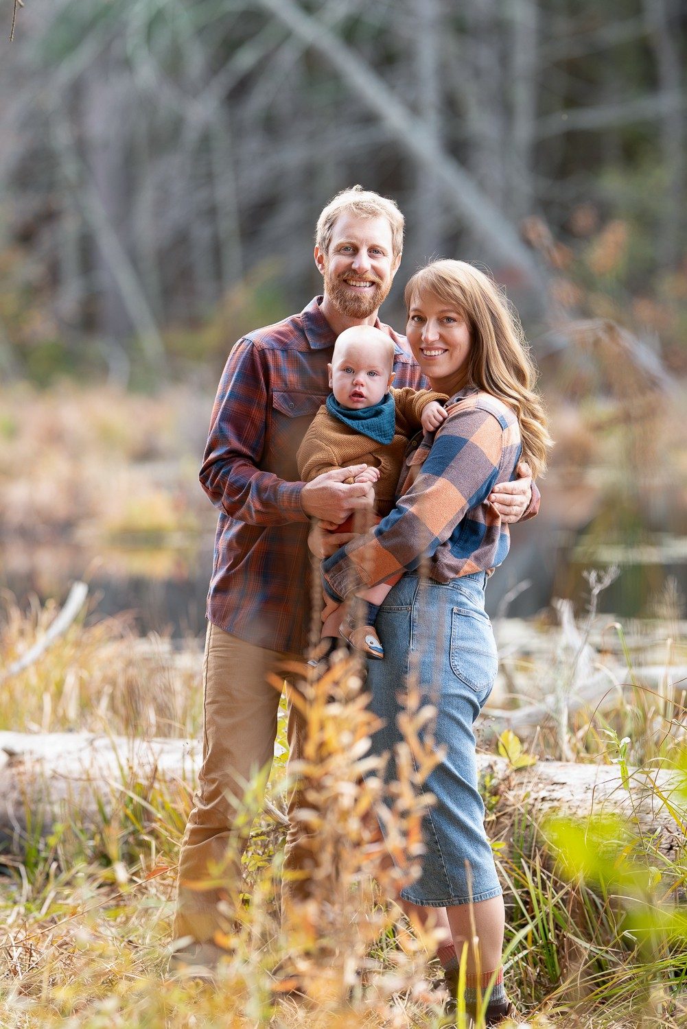 Family of three in tawny autumn grass with bare trees behind at Assabet River National Wildlife Refuge, Sudbury Massachusetts