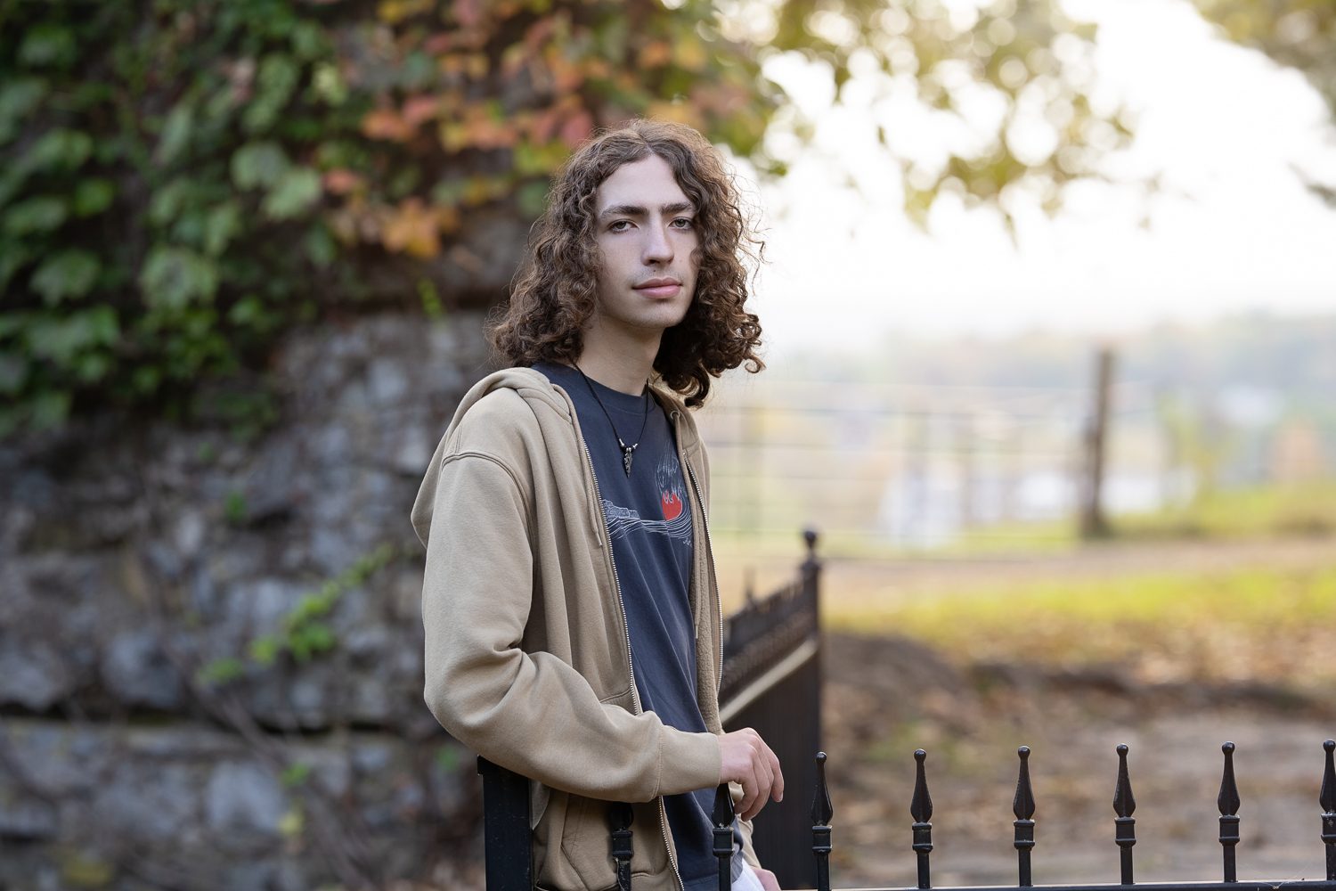 Senior leaning against stone wall ruins of Bancroft's Castle and golden autumn trees behind them in Groton MA, photographed by Chelmsford portrait photographer Luciana Calvin