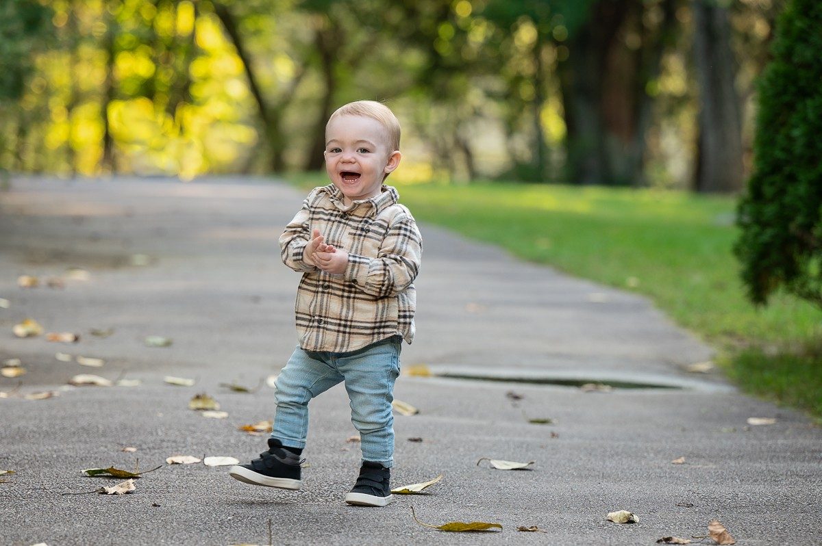 Toddler walking alone along the paved path in autumn at Benson Park, Hudson New Hampshire