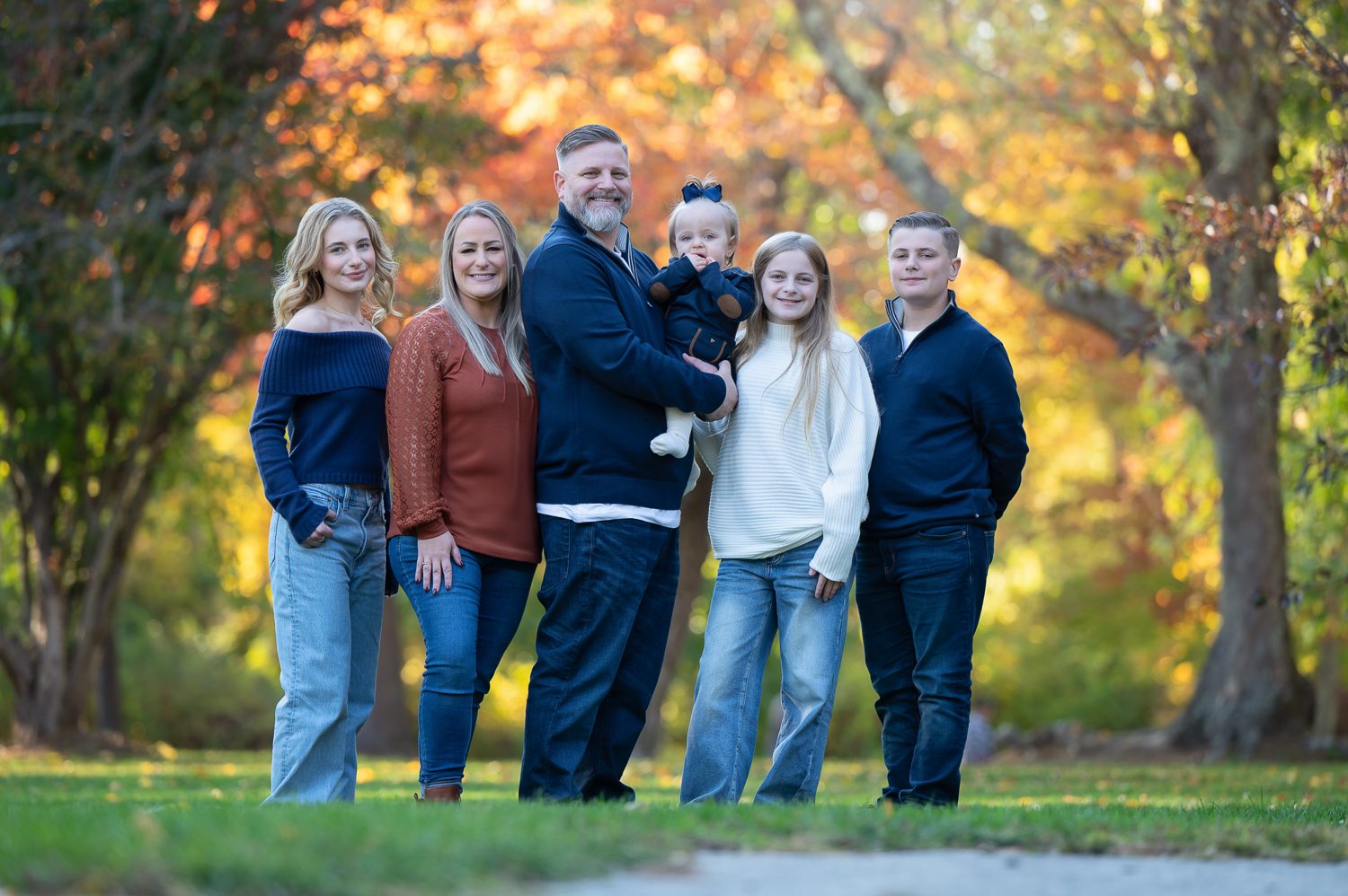 Large extended family standing together among tall pines in golden evening light at Benson Park, Hudson New Hampshire