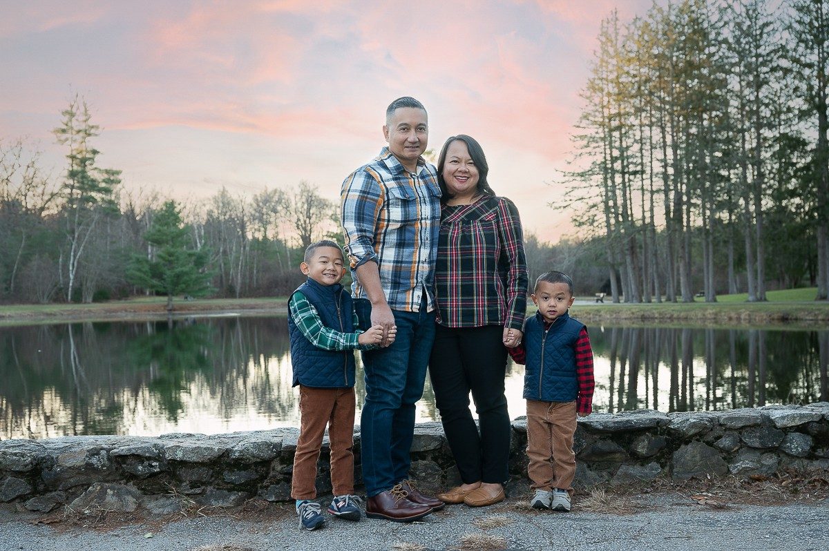 Family of four on the stone wall at the pond at sunset at Benson Park in Hudson NH
