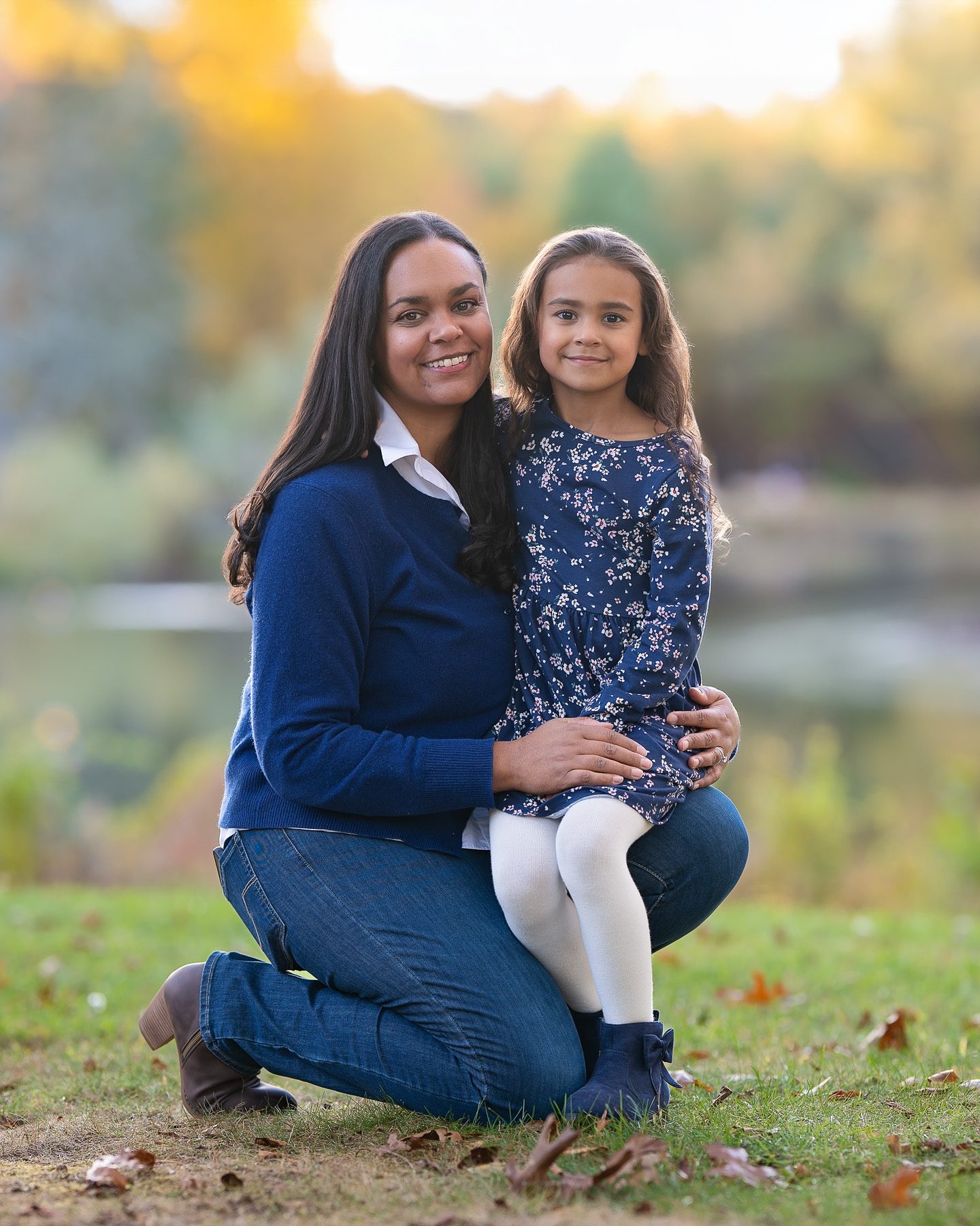 Mother kneeling with her daughter beside the pond in autumn at Benson Park in Hudson NH
