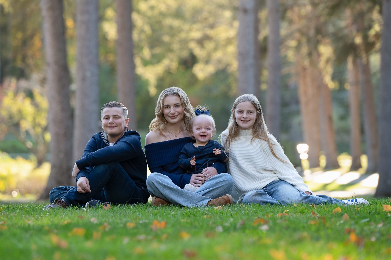 Family group sitting together on the grass in golden light at Benson Park in Hudson NH