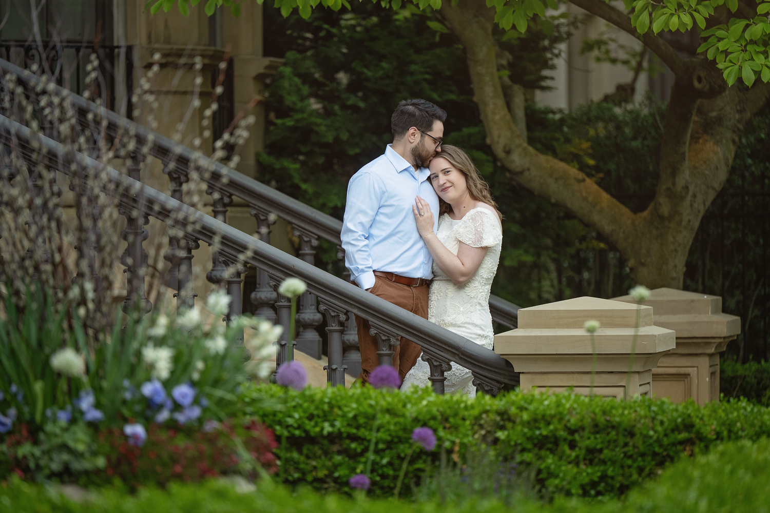 Couple embracing on the steps of a Back Bay brownstone with spring flowers and an iron railing in Boston MA