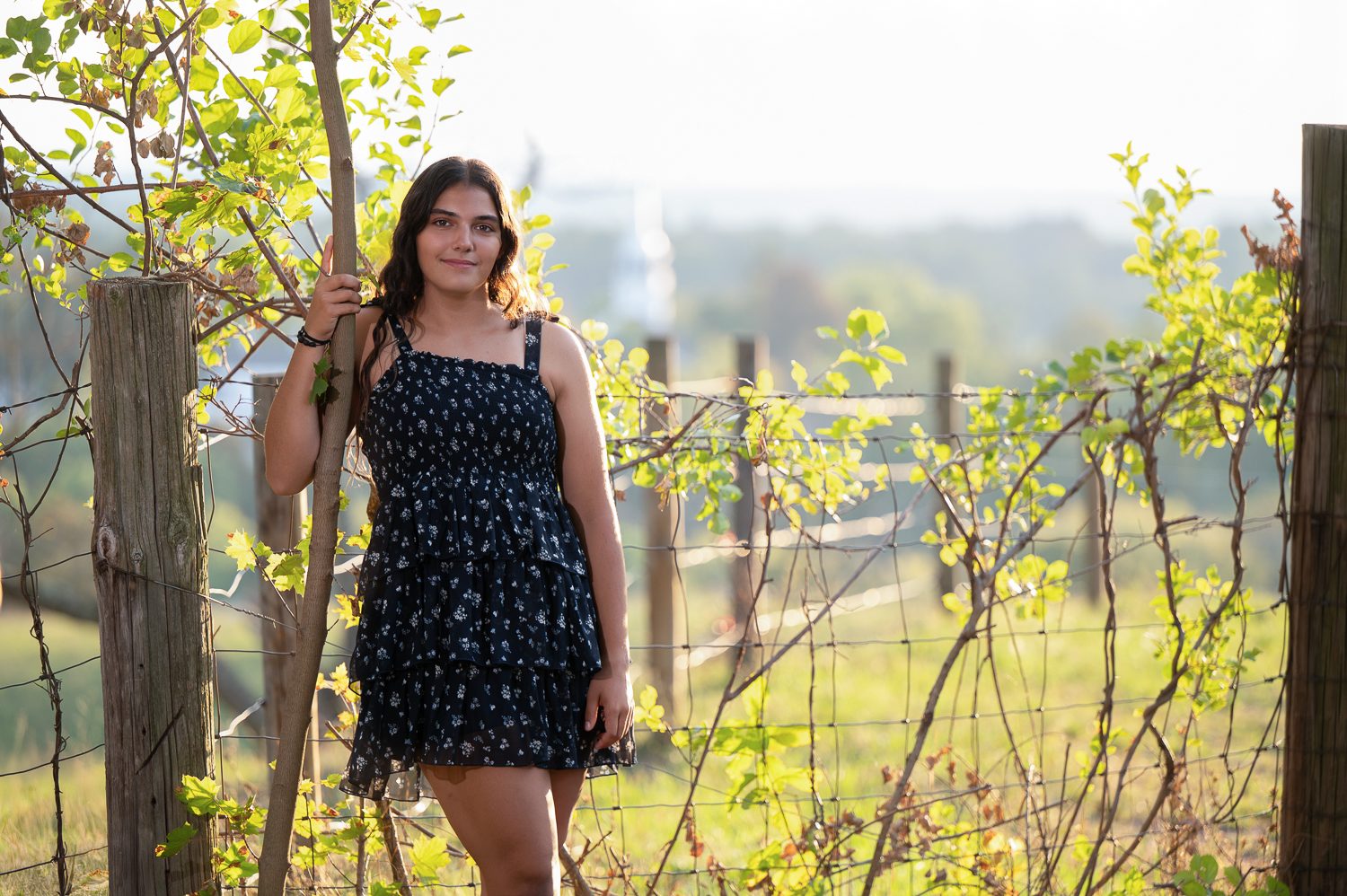 High school senior leaning on the split-rail pasture fence in autumn on Gibbet Hill, Groton Massachusetts