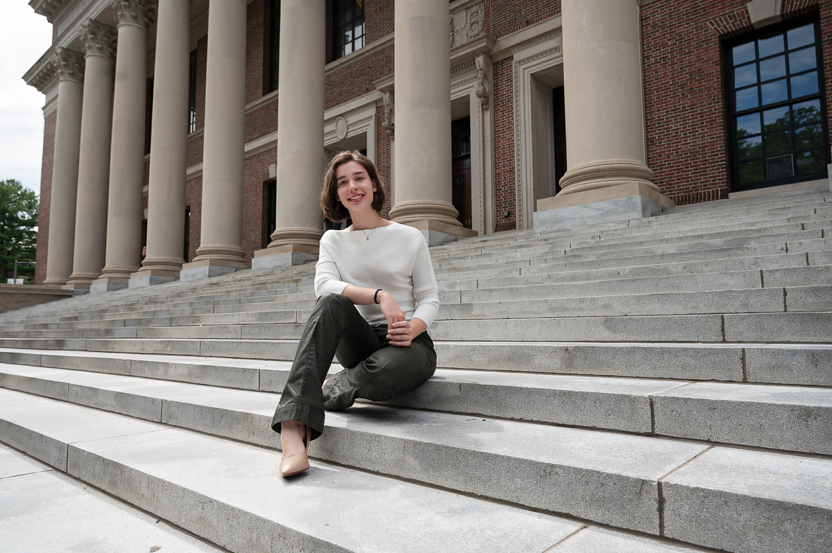 High school senior seated on the granite steps below the colonnade of Widener Library in Harvard Yard in Cambridge MA