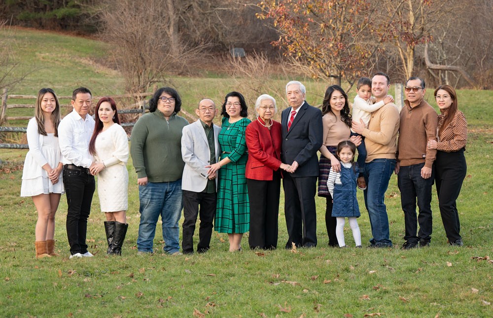 Large extended family of fourteen standing together on the lawn in late autumn at Red Wing Farm Reservation in Chelmsford MA