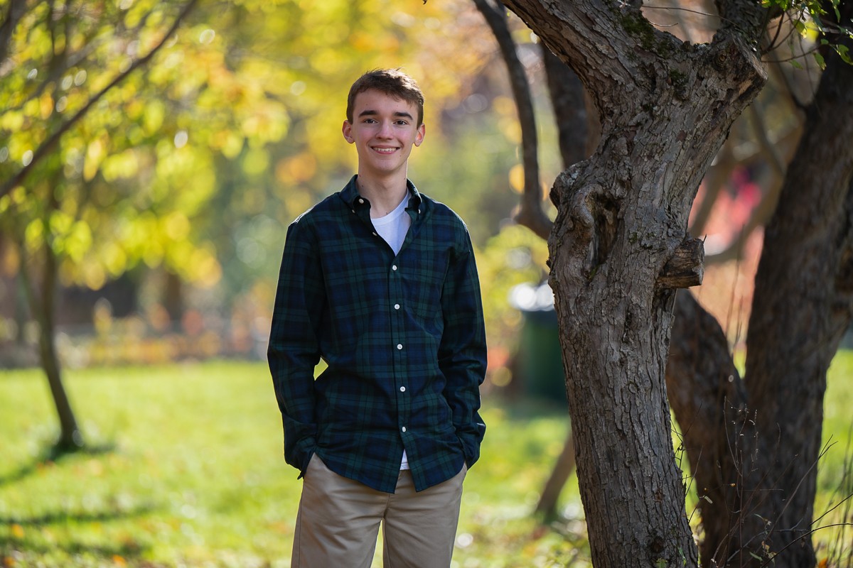 High school senior beside a large multi-trunk tree beside the Bruce Freeman Rail Trail at Red Wing Farm Reservation in Chelmsford MA