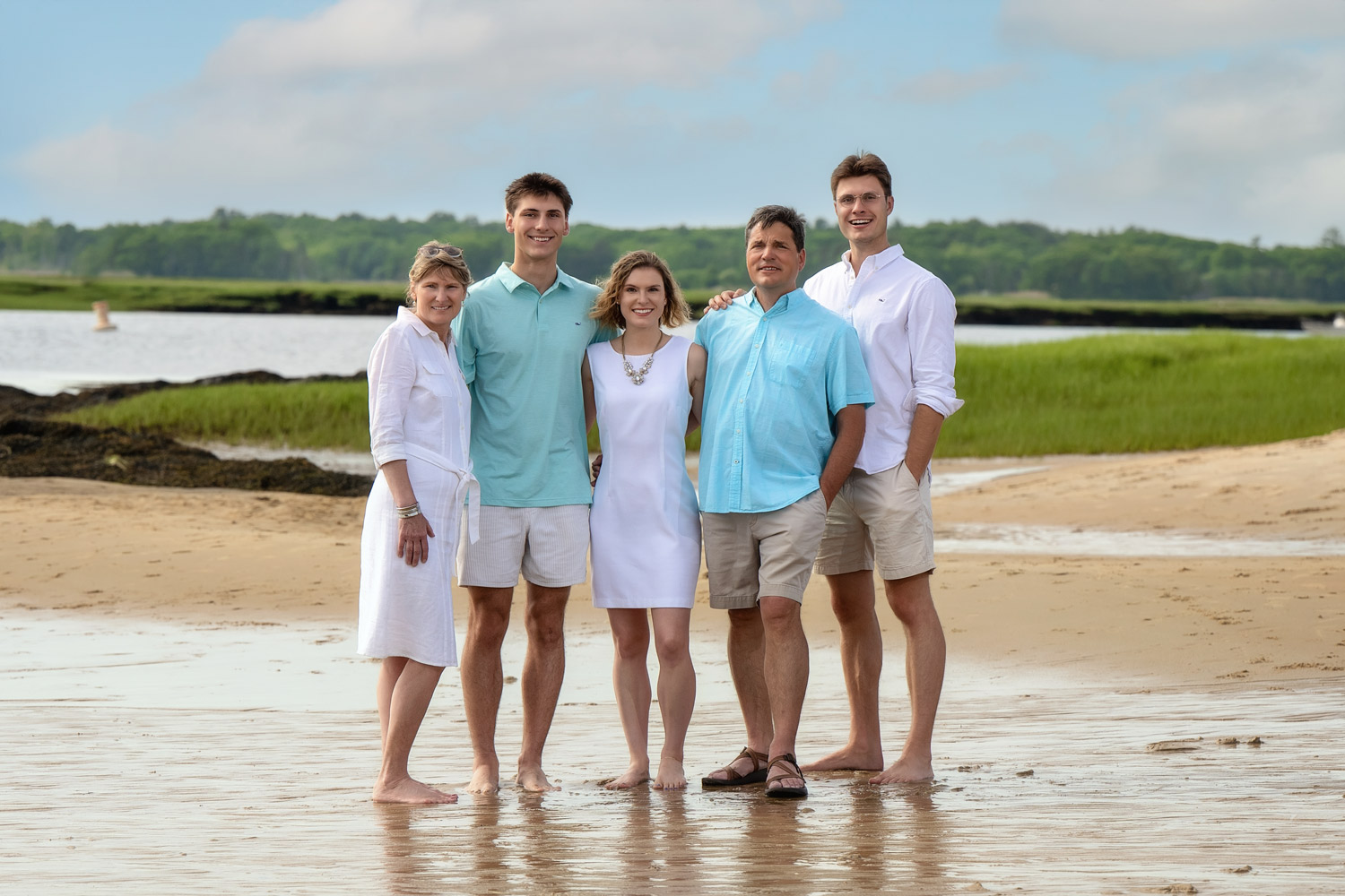Family of five on the tidal flats with the salt marsh behind them at Salisbury Beach in Salisbury MA