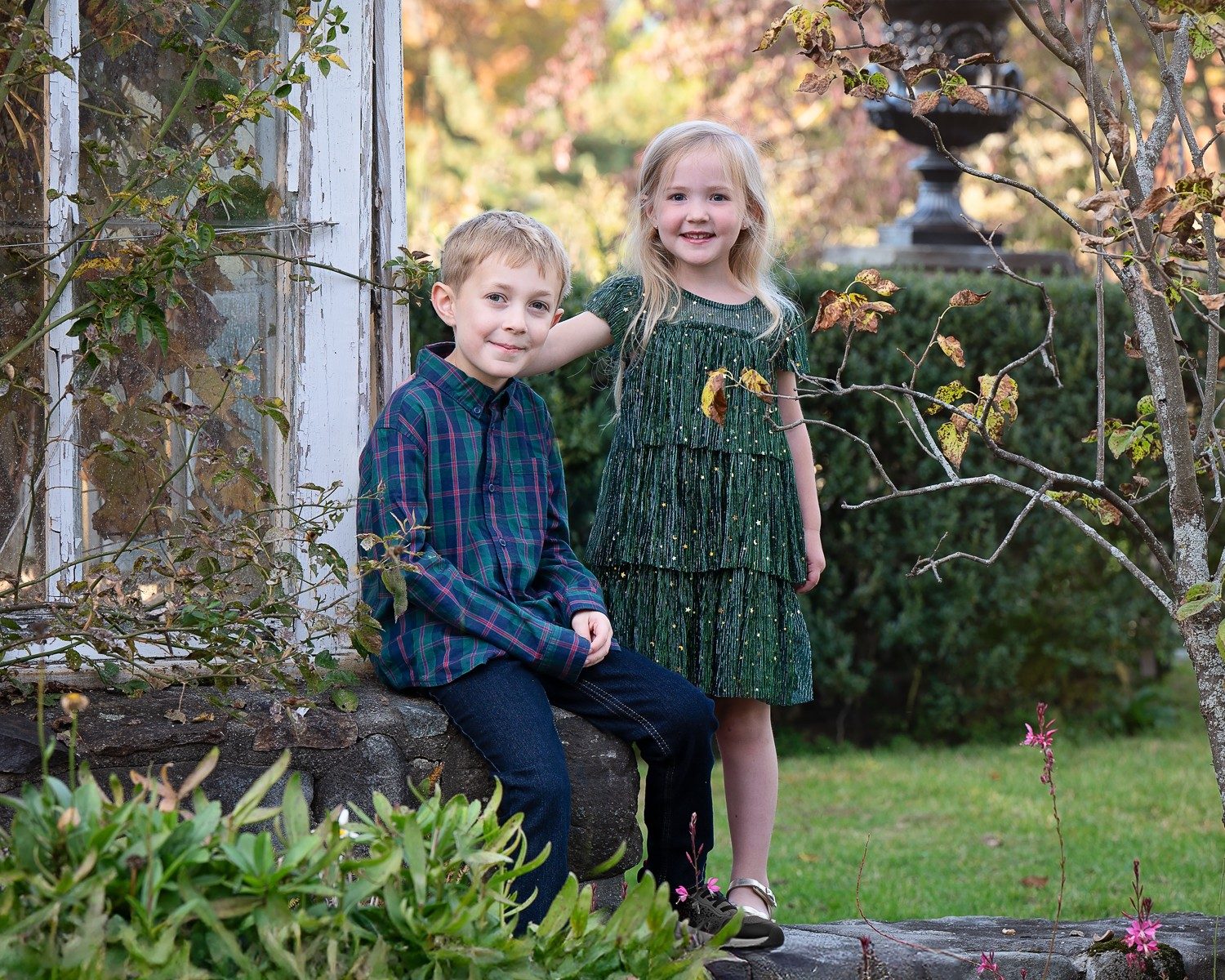 Brother and sister beside the house with a stone garden urn and shrubs behind them at Stevens-Coolidge House and Gardens in North Andover Massachusetts