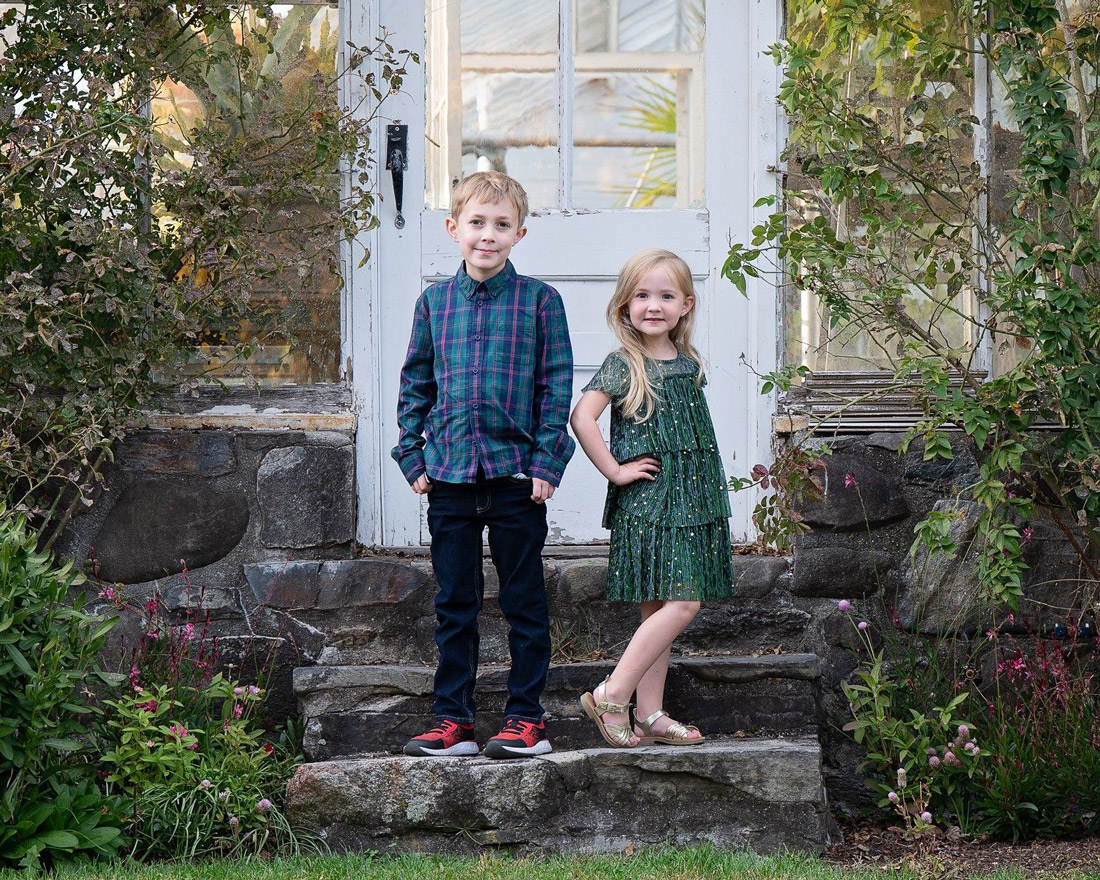 Young brother and sister standing on the rough stone steps at the white clapboard door of the house at Stevens-Coolidge in North Andover MA