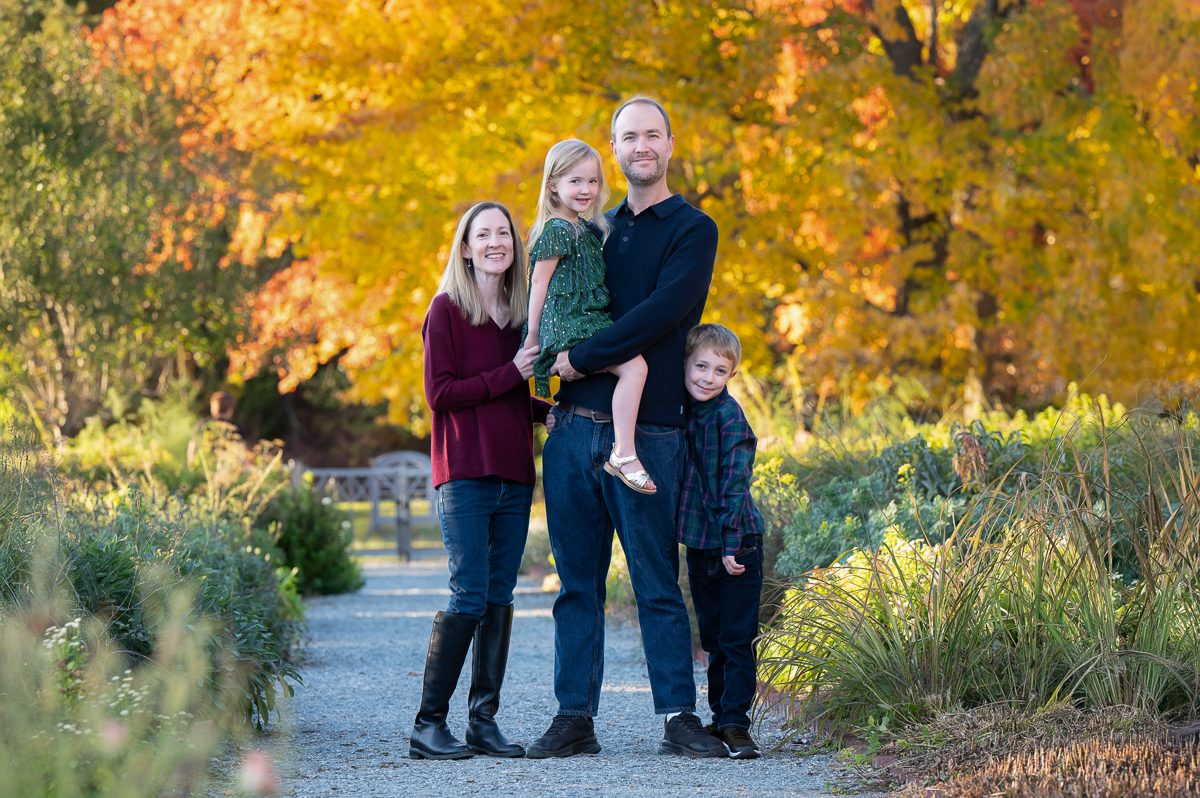 Family walking under a golden autumn canopy at Stevens-Coolidge House and Gardens in North Andover MA