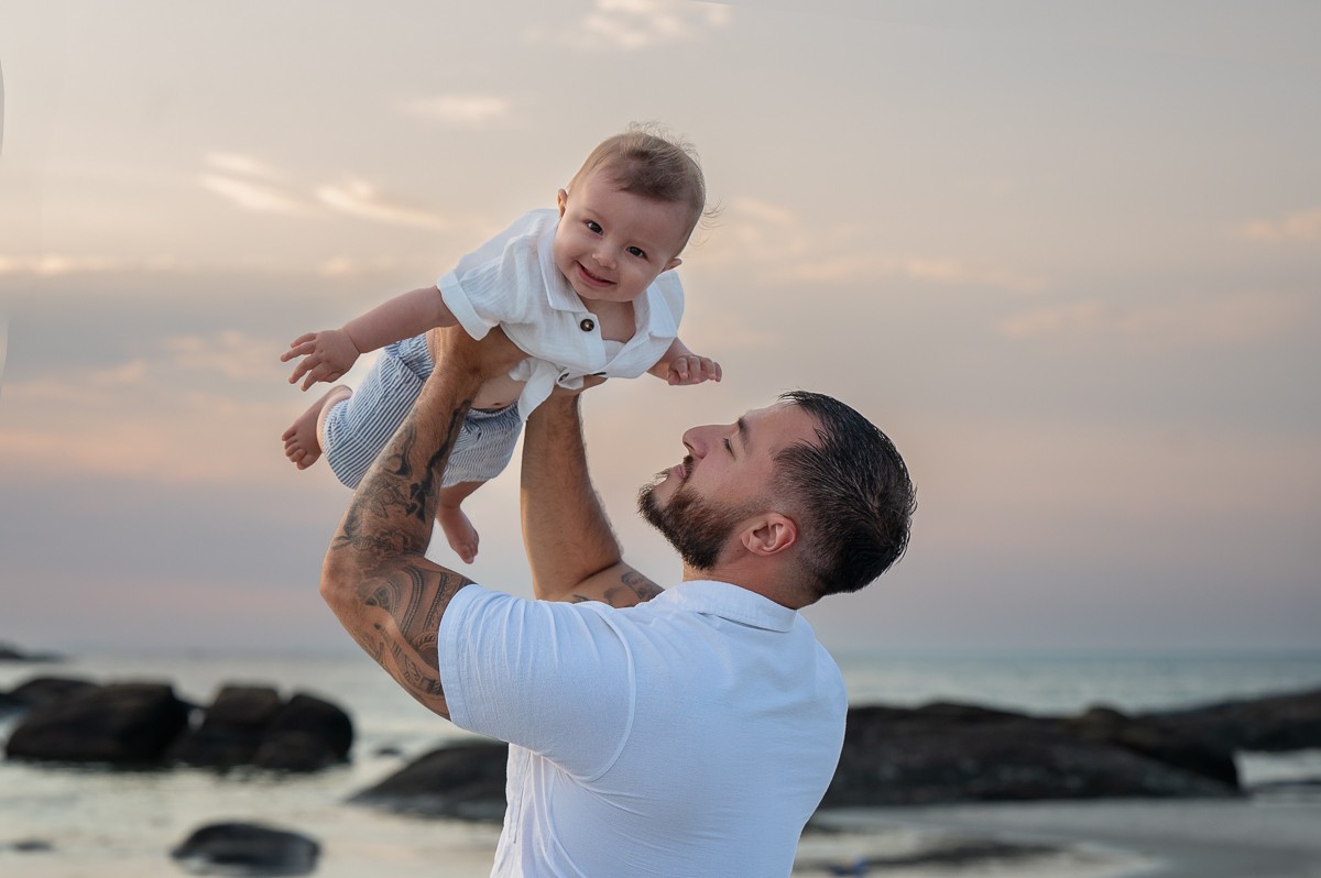 Father lifting his baby overhead against the evening sky at Wingaersheek Beach, Gloucester MA