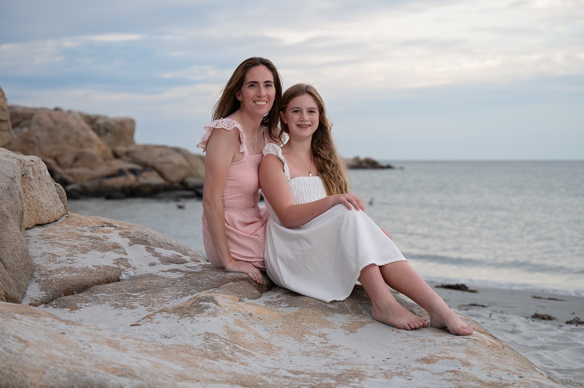 Mother and teenage daughter seated on the granite ledge at Wingaersheek Beach in Gloucester Massachusetts