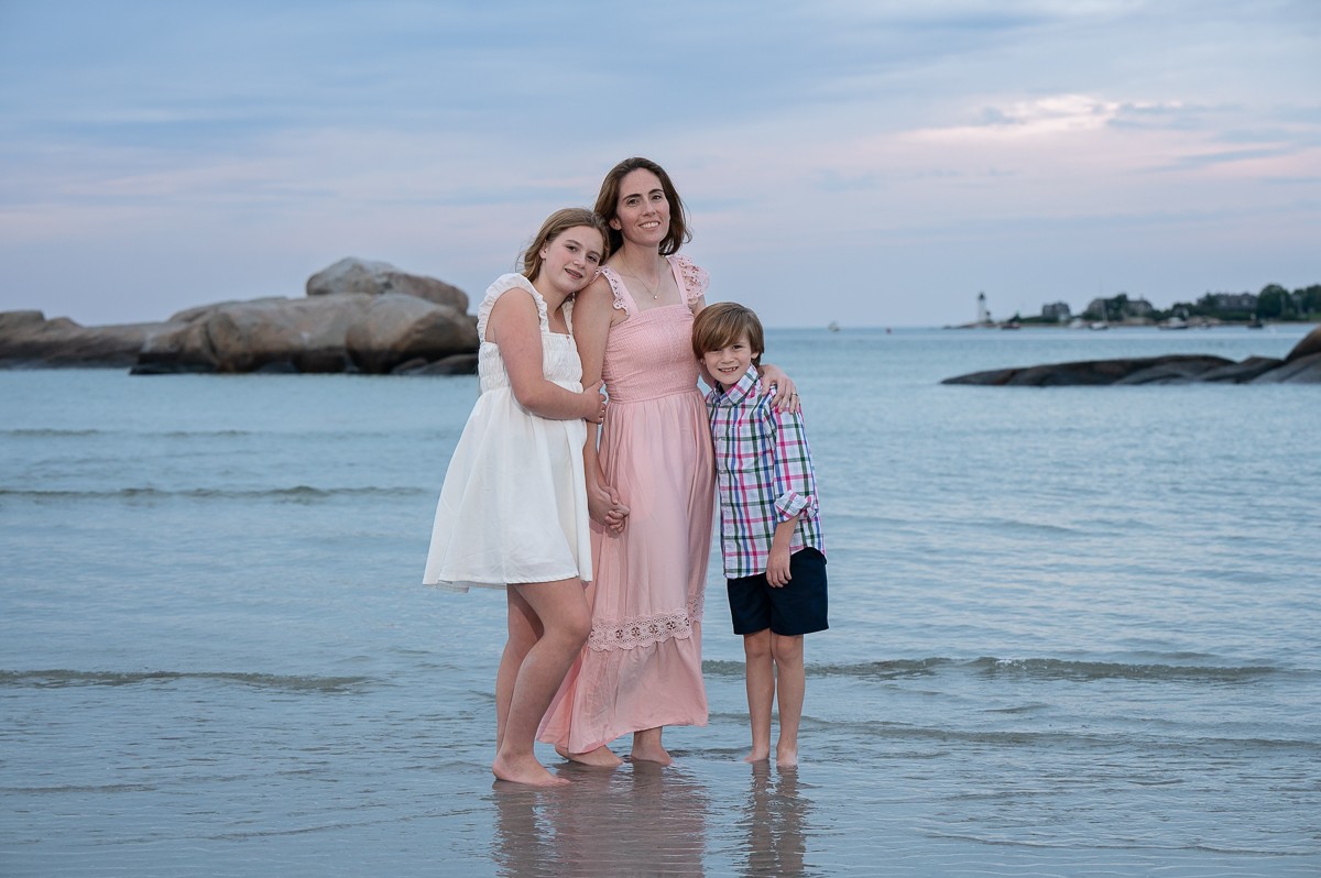 Mother with her son and daughter reflected in the wet sand at low tide at Wingaersheek Beach in Gloucester MA